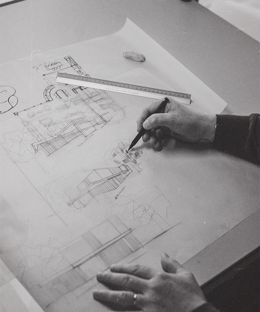 Hands sketching architectural designs, using a pencil and ruler, highlighting meticulous planning and attention to detail.