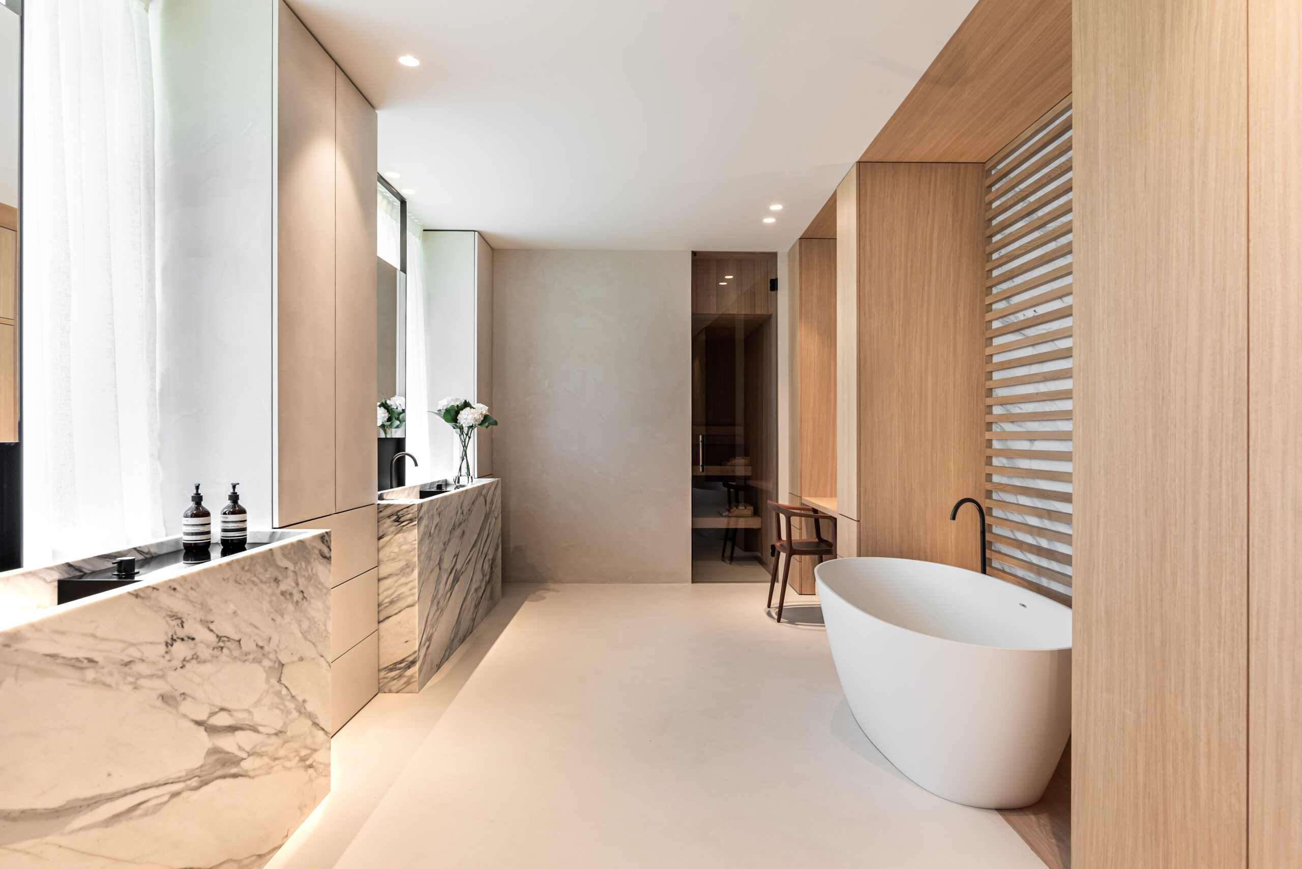 Modern bathroom with a marble countertop, wooden panels, and a standalone white bathtub