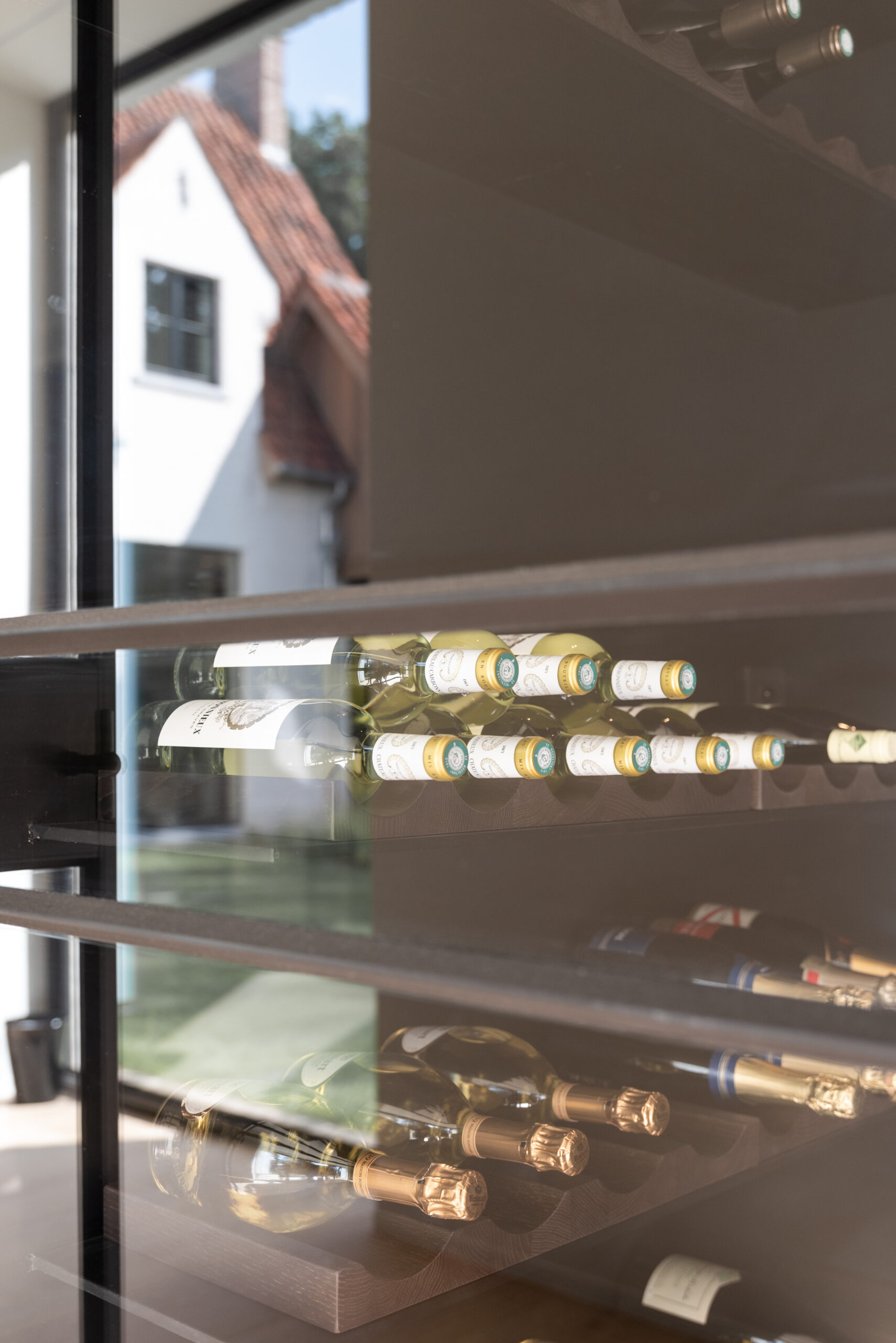 Wine bottles displayed in a sleek glass cabinet.