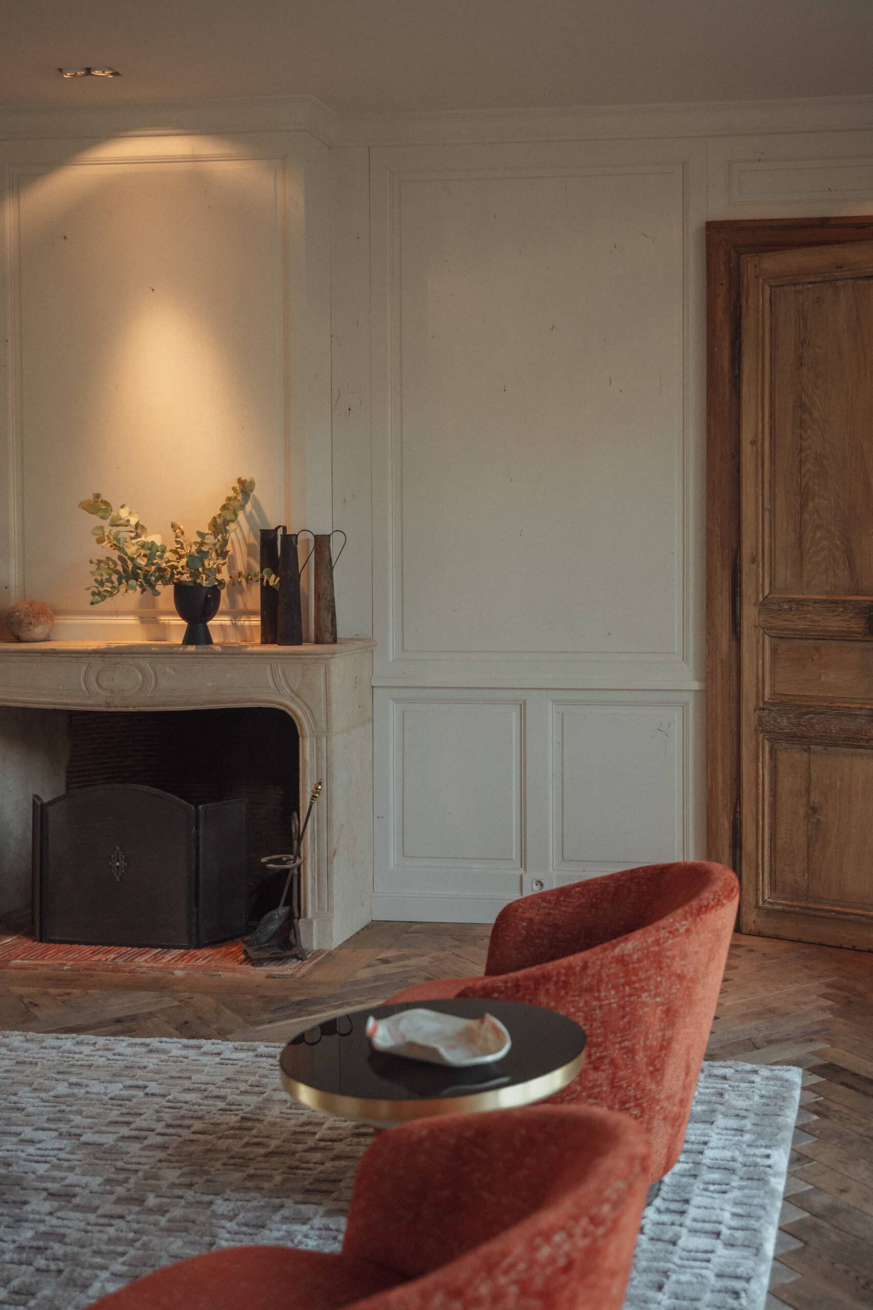 Een huis in Tudorstijl met bakstenen en houten details kijkt uit over een rustig zwembad, omlijst door keurig bijgesnoeide groene struiken en hoge bomen.