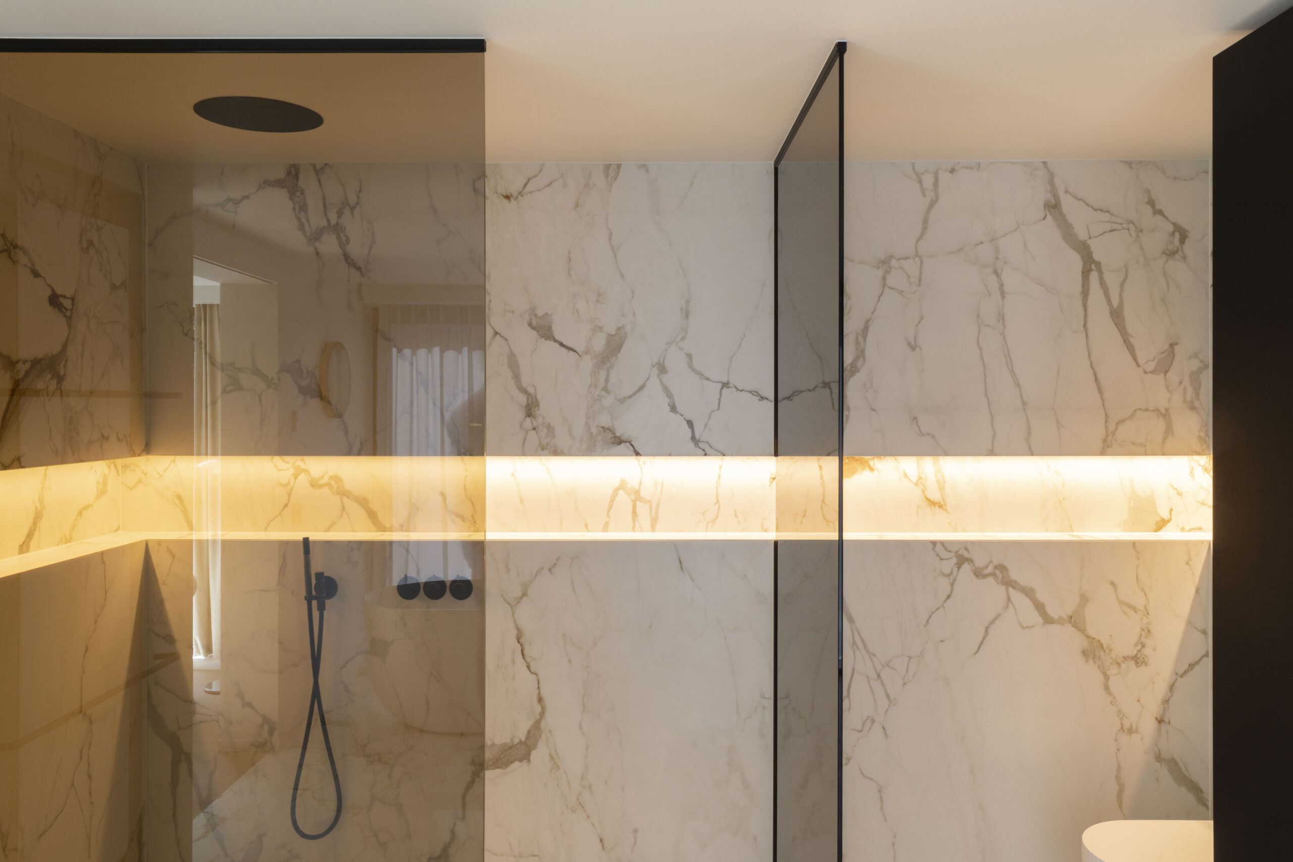 A luxurious bathroom with elegant marble walls, ambient lighting, and modern fixtures.
