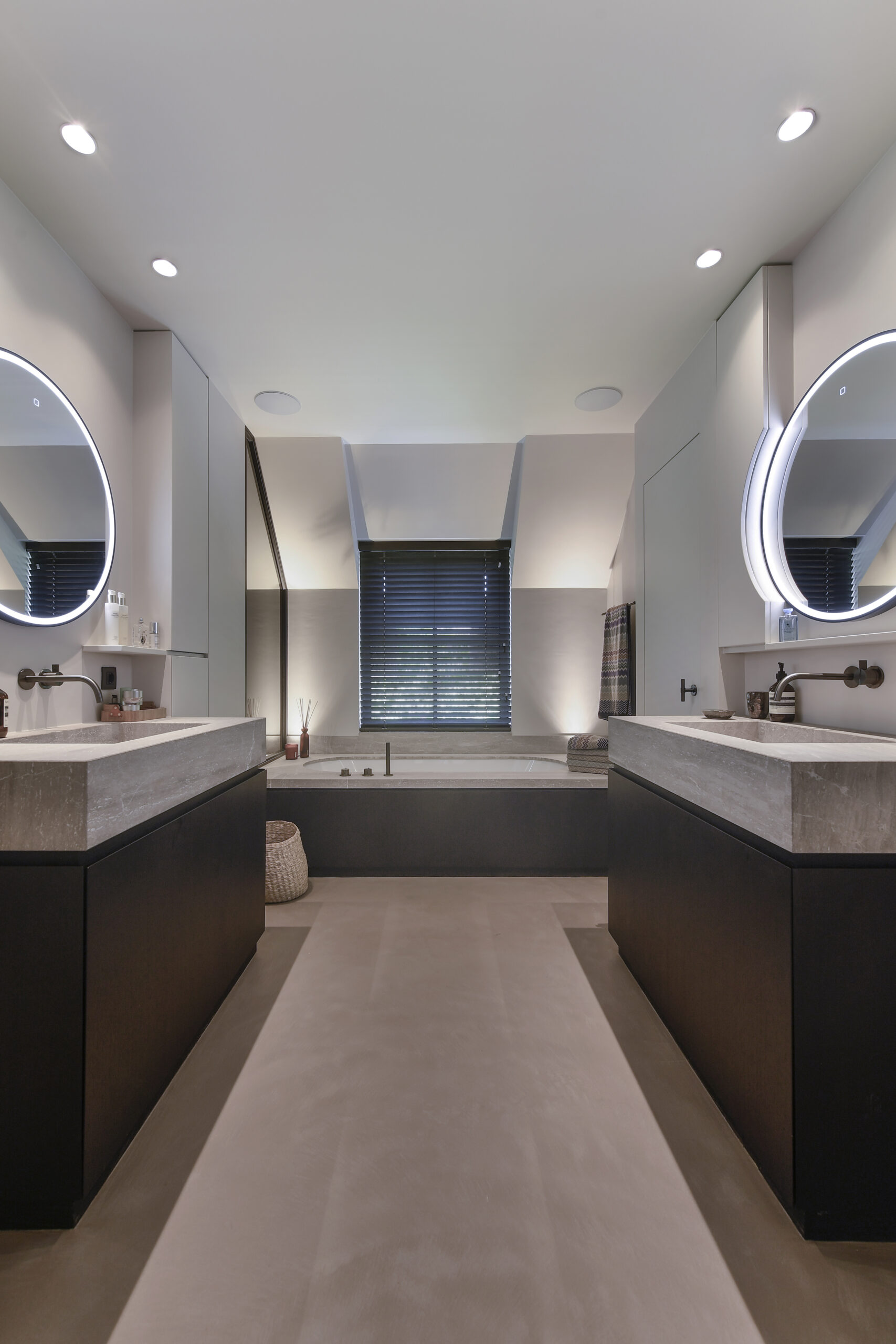 Modern bathroom with dual sinks, illuminated mirrors, and a built-in bathtub.