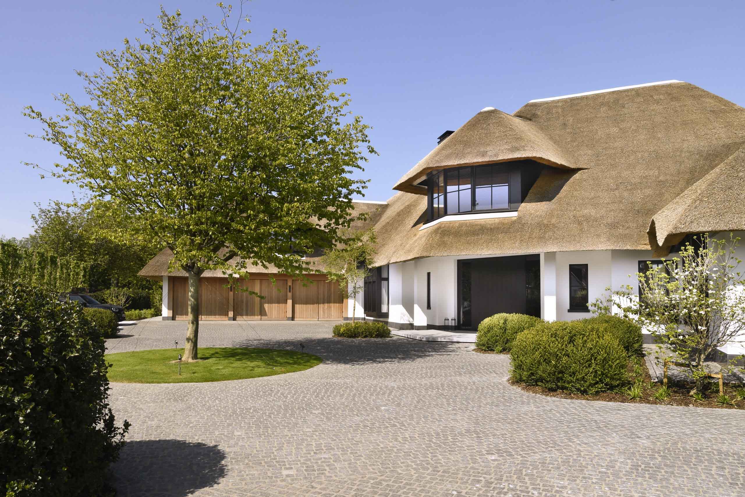 Modern house with thatched roof, cobblestone driveway, and green tree.Modern house with thatched roof, cobblestone driveway, and green tree.