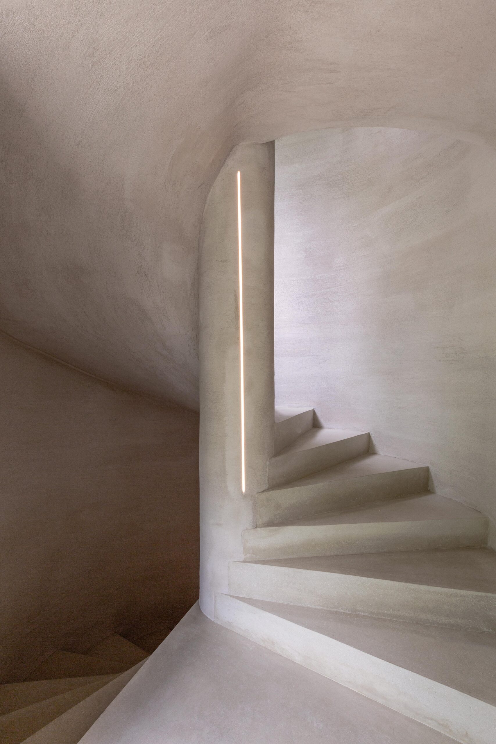 Een minimalistische trap met zachte verlichting en glad gestuukte muren.