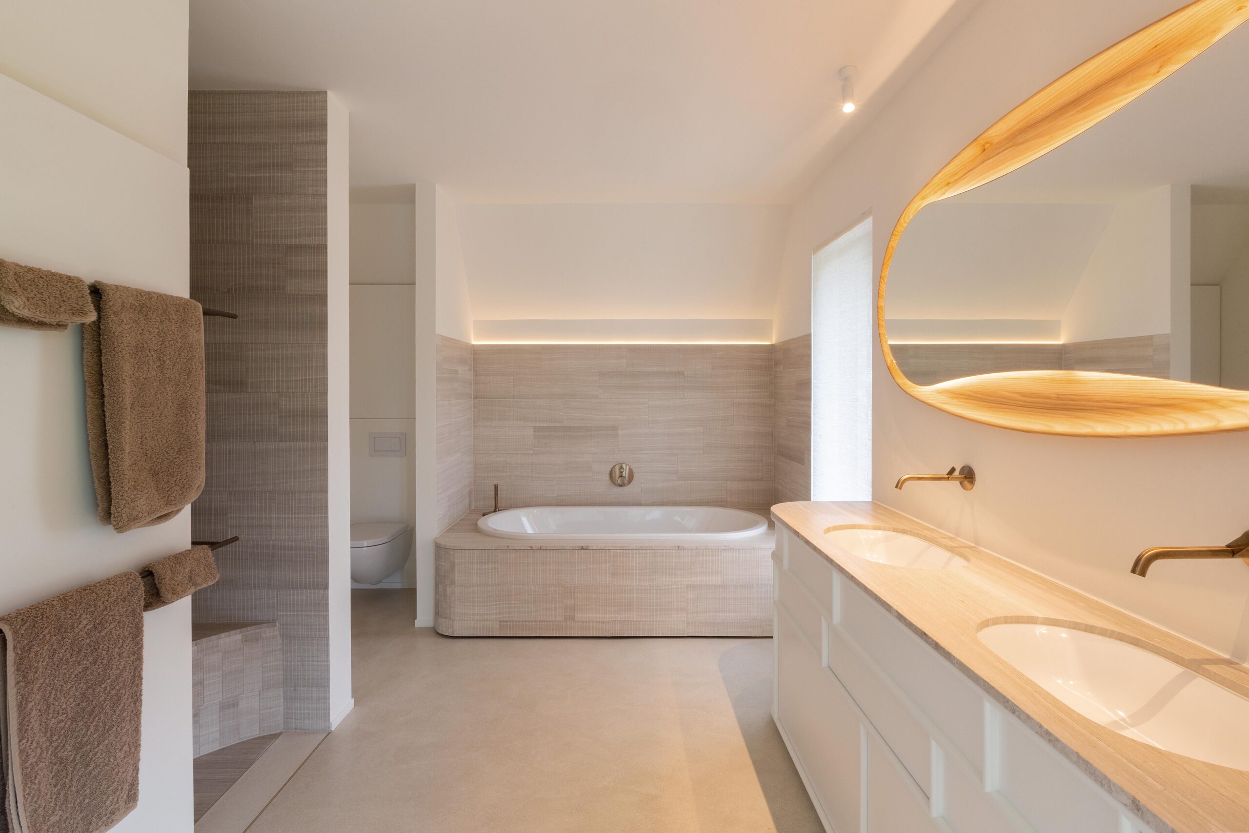 Een elegante badkamer met een unieke spiegel, ingebouwd bad en warme verlichting.