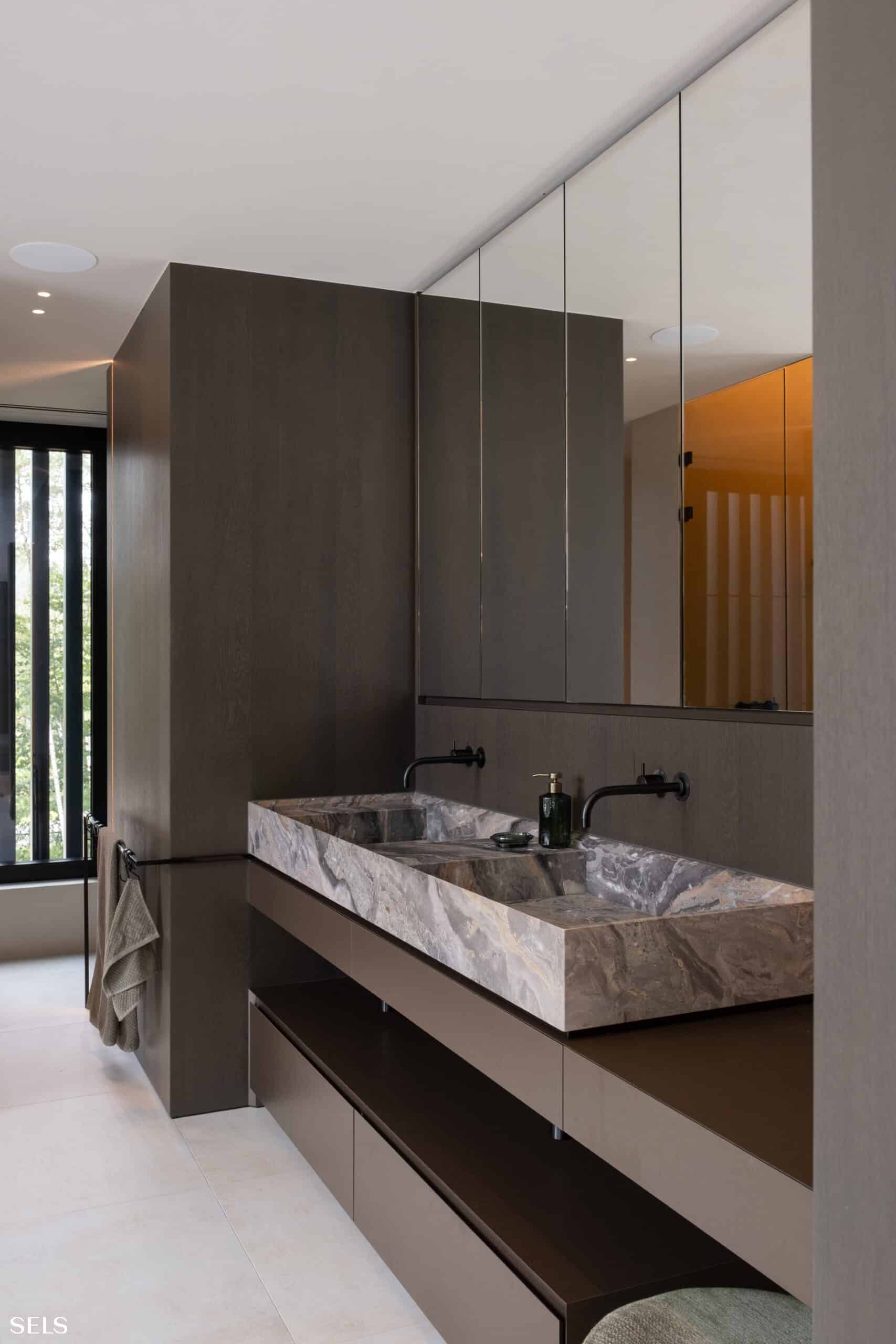 Luxe badkamer met een vrijstaand bad, moderne inloopdouche, donkere accenten en een strakke, minimalistische afwerking, gerealiseerd door Sels Villabouw.